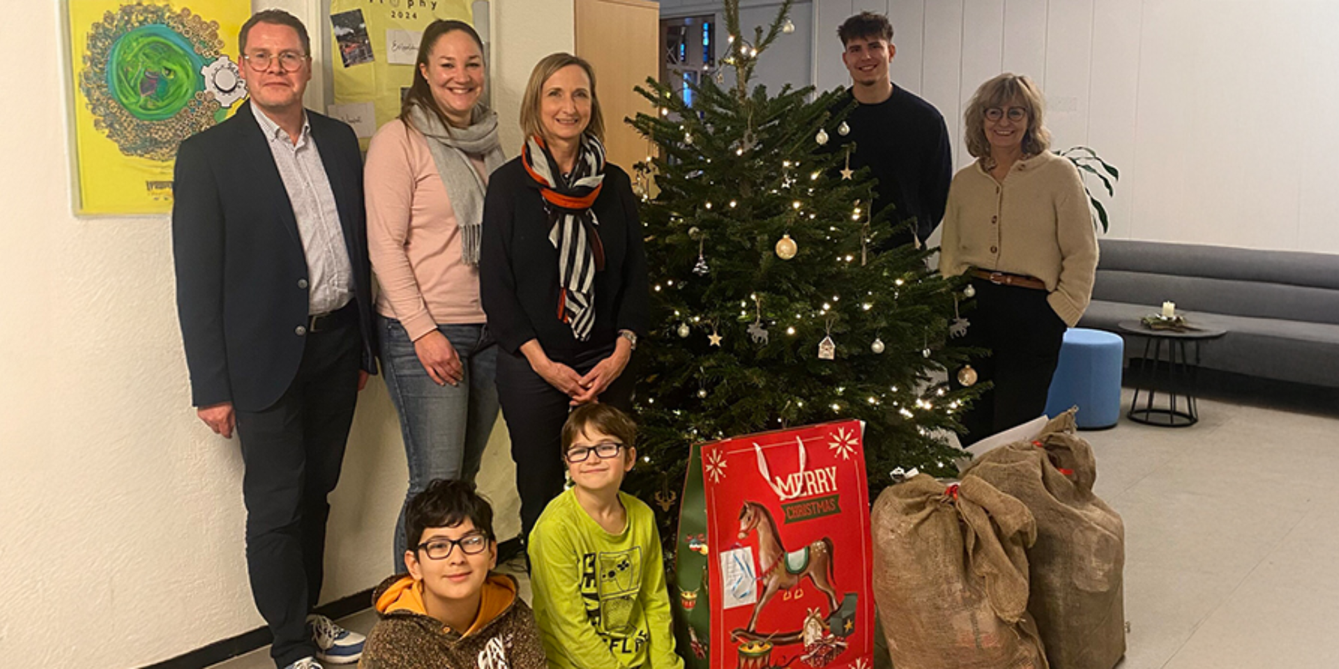 UnionStahl Wunschbaumaktion: Mitarbeiter und Kinder vor einem geschmückten Weihnachtsbaum mit Geschenken.